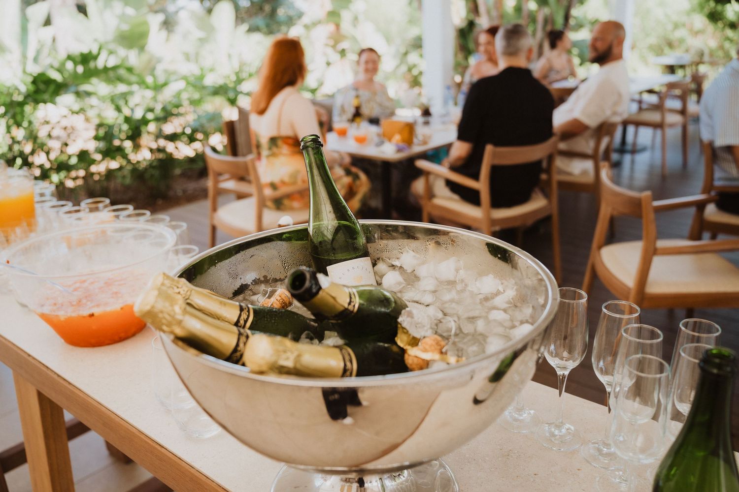 Champagne bottles chilling in an ice bucket on a rustic wooden table with glassware.