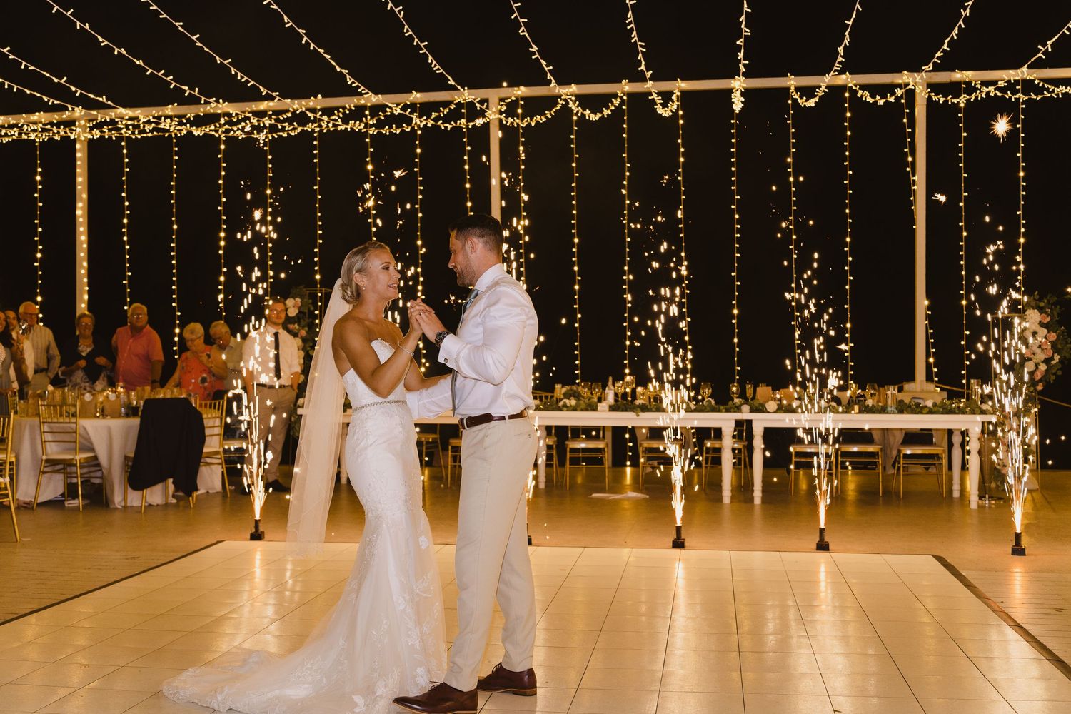Newlyweds share an intimate dance under elegant string light decorations at their reception.