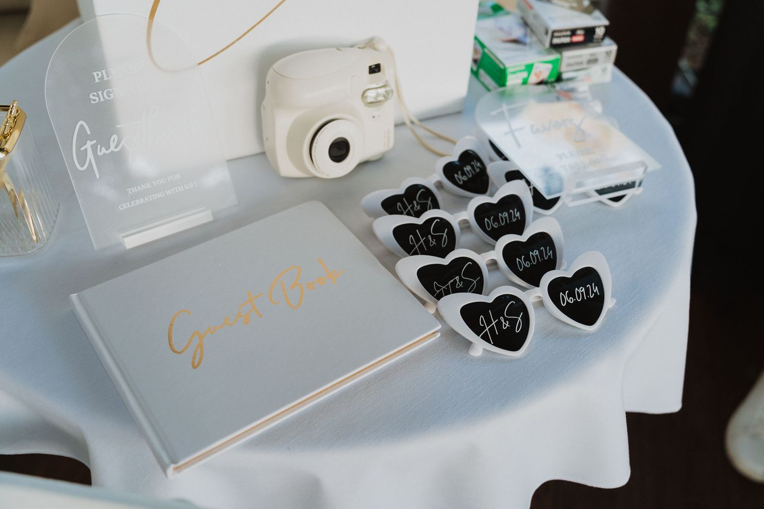Black heart-shaped name cards and a gold guest book displayed on a white tablecloth for wedding decor.