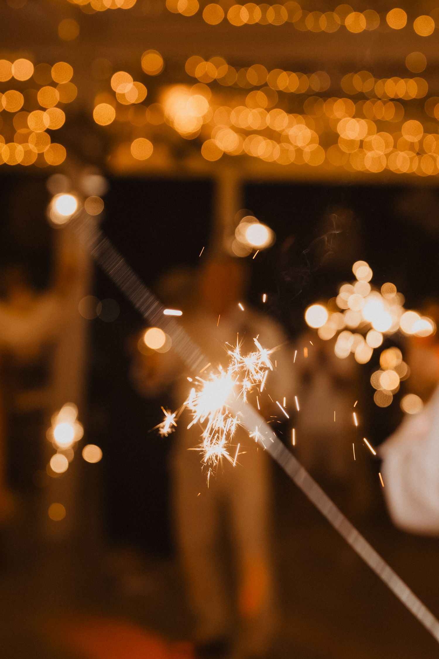 Close-up shot of a sparkler creating magical light trails against bokeh background.