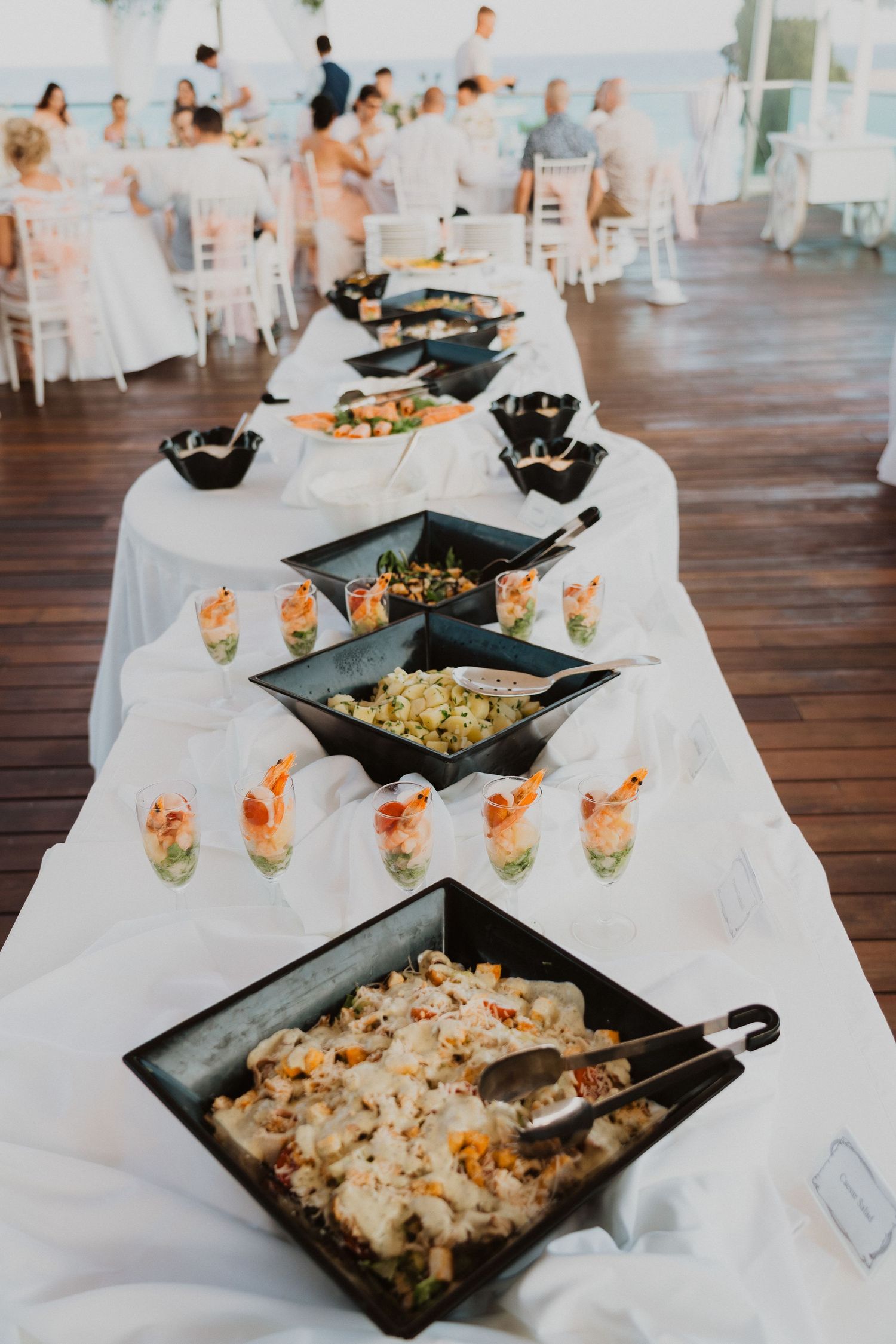 Buffet table with elegant appetizers and seafood dishes displayed on black platters.