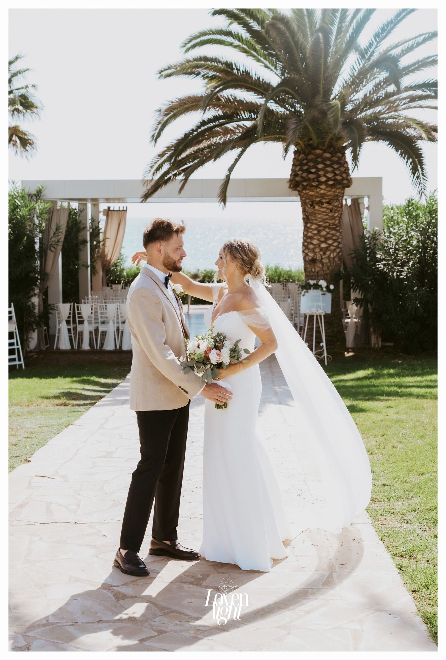 Newlyweds share an intimate moment under a palm tree at their outdoor wedding venue.