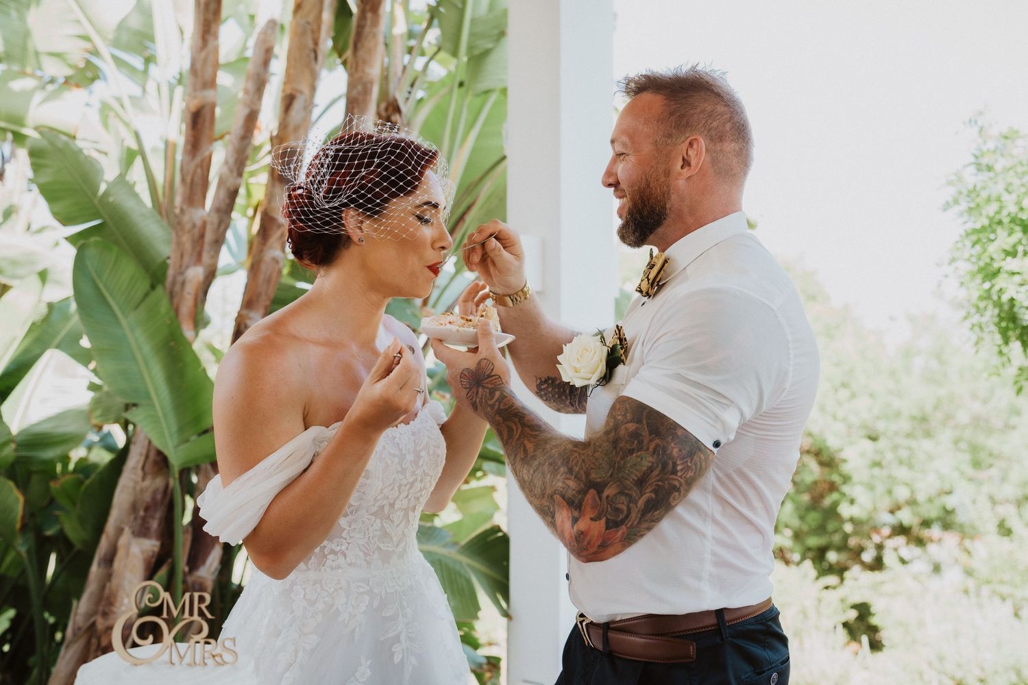 Playful couple feeding each other cake during their wedding celebration.
