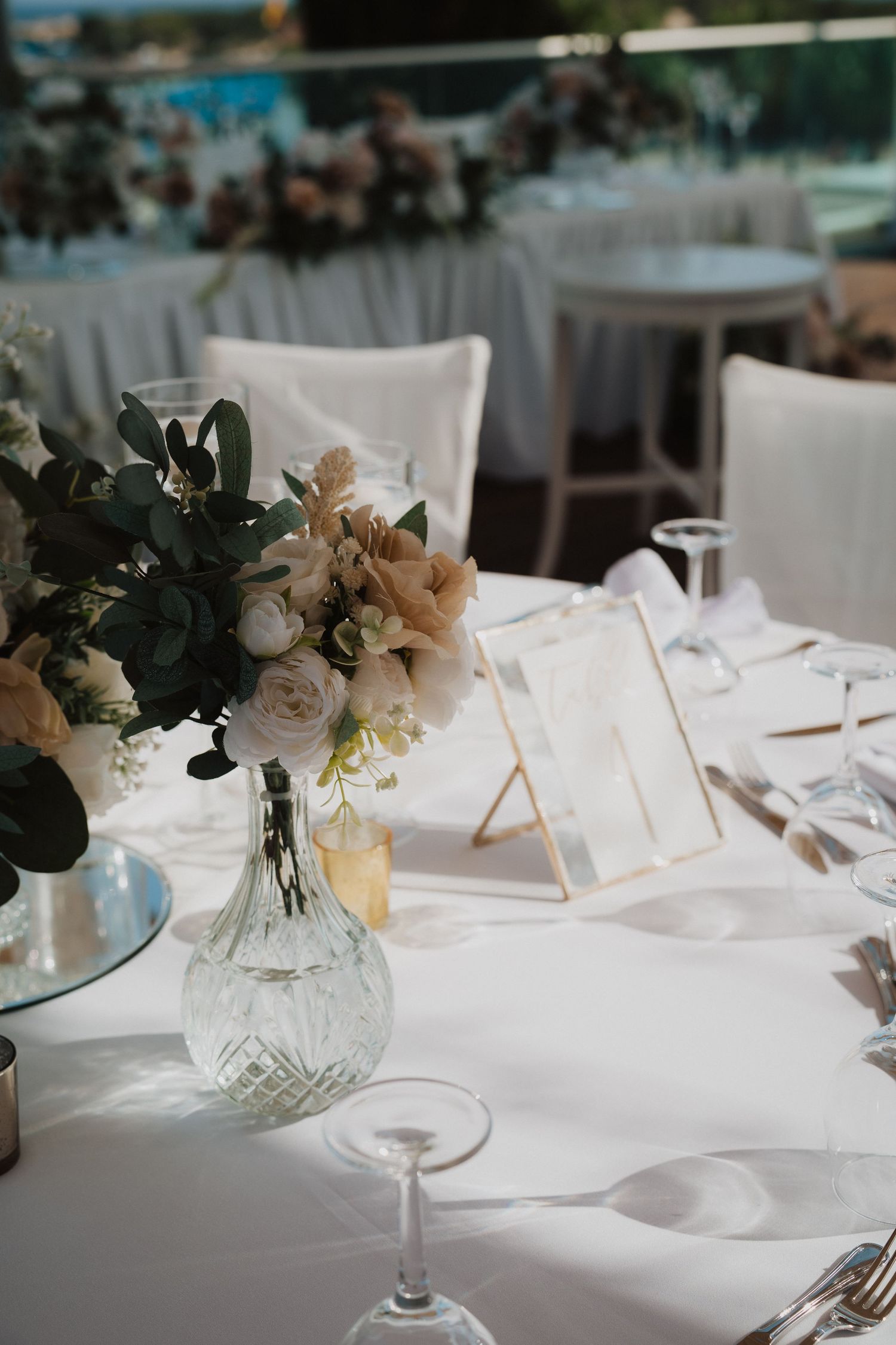 Coastal wedding reception setup with soft blue and white decor and floral centerpieces.