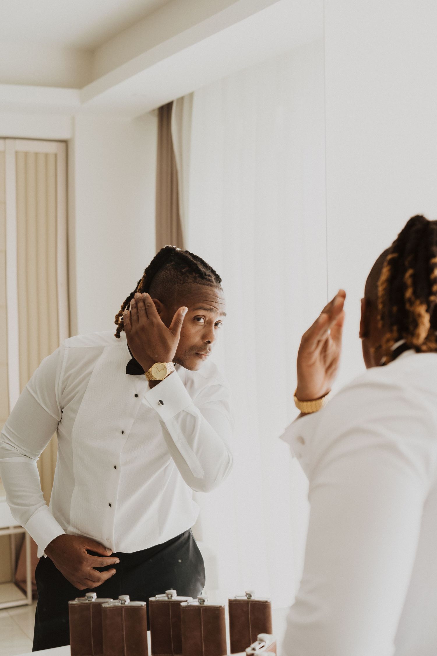 Person in white dress shirt and black pants checking their appearance before formal event.