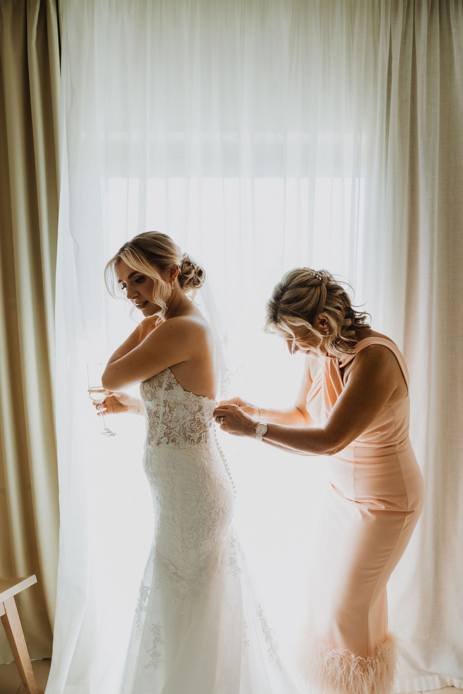 Close-up sequence showing the buttoning of an elegant white lace wedding dress with delicate details.