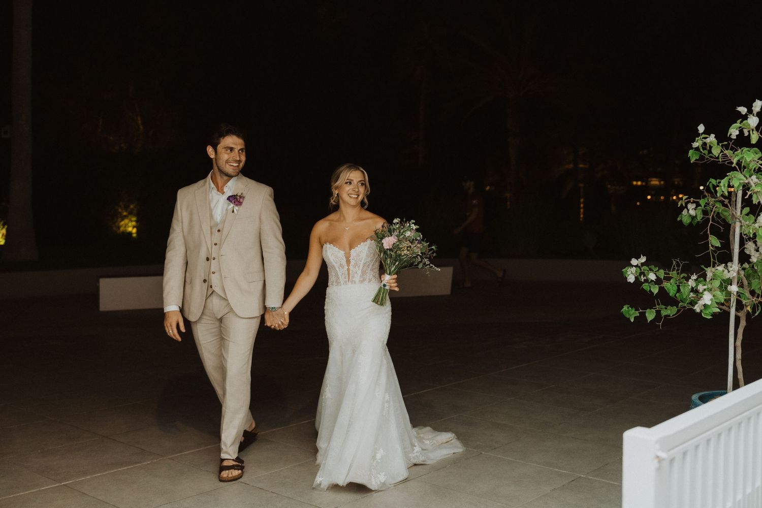 Couple walking together at night in formal wedding attire.