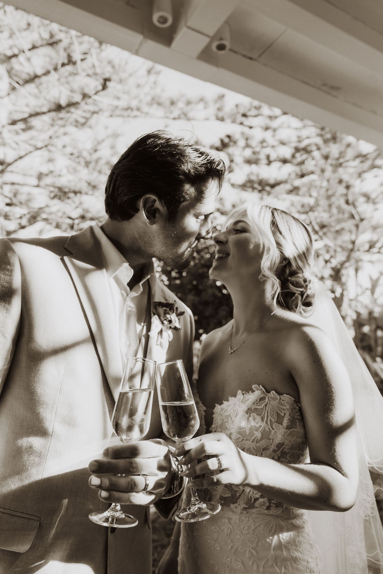 Black and white photo of newlyweds sharing champagne during their reception.