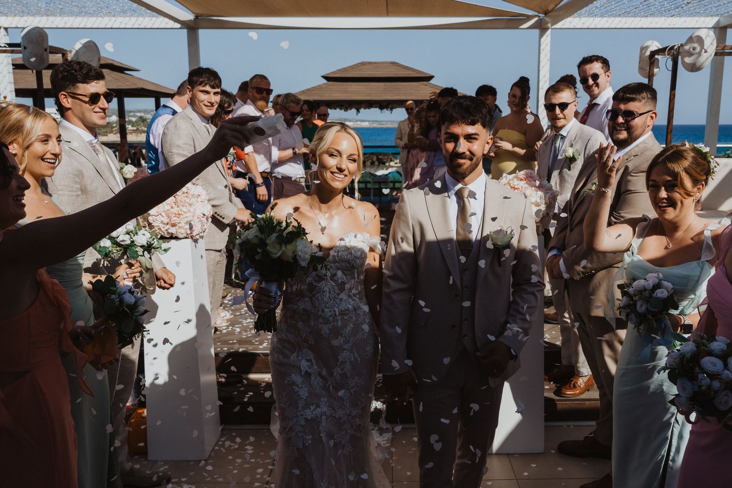 Celebratory moment with confetti being thrown at a waterfront wedding ceremony.