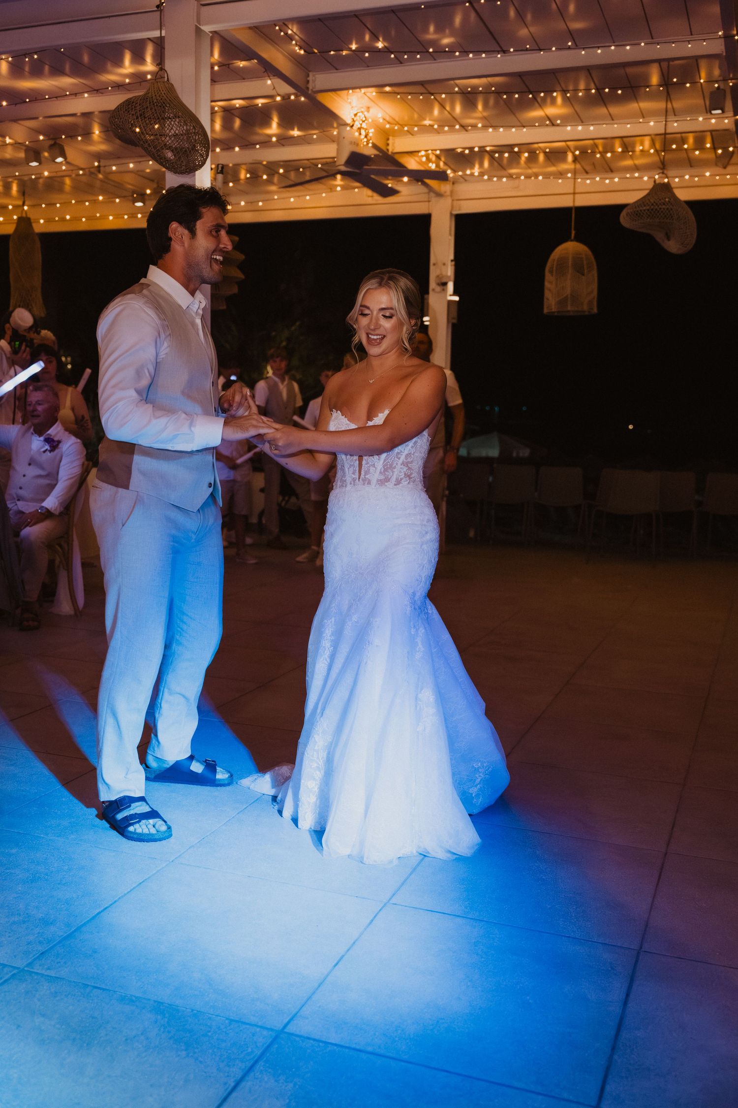 Couples dancing on illuminated floor with blue lighting at wedding reception.