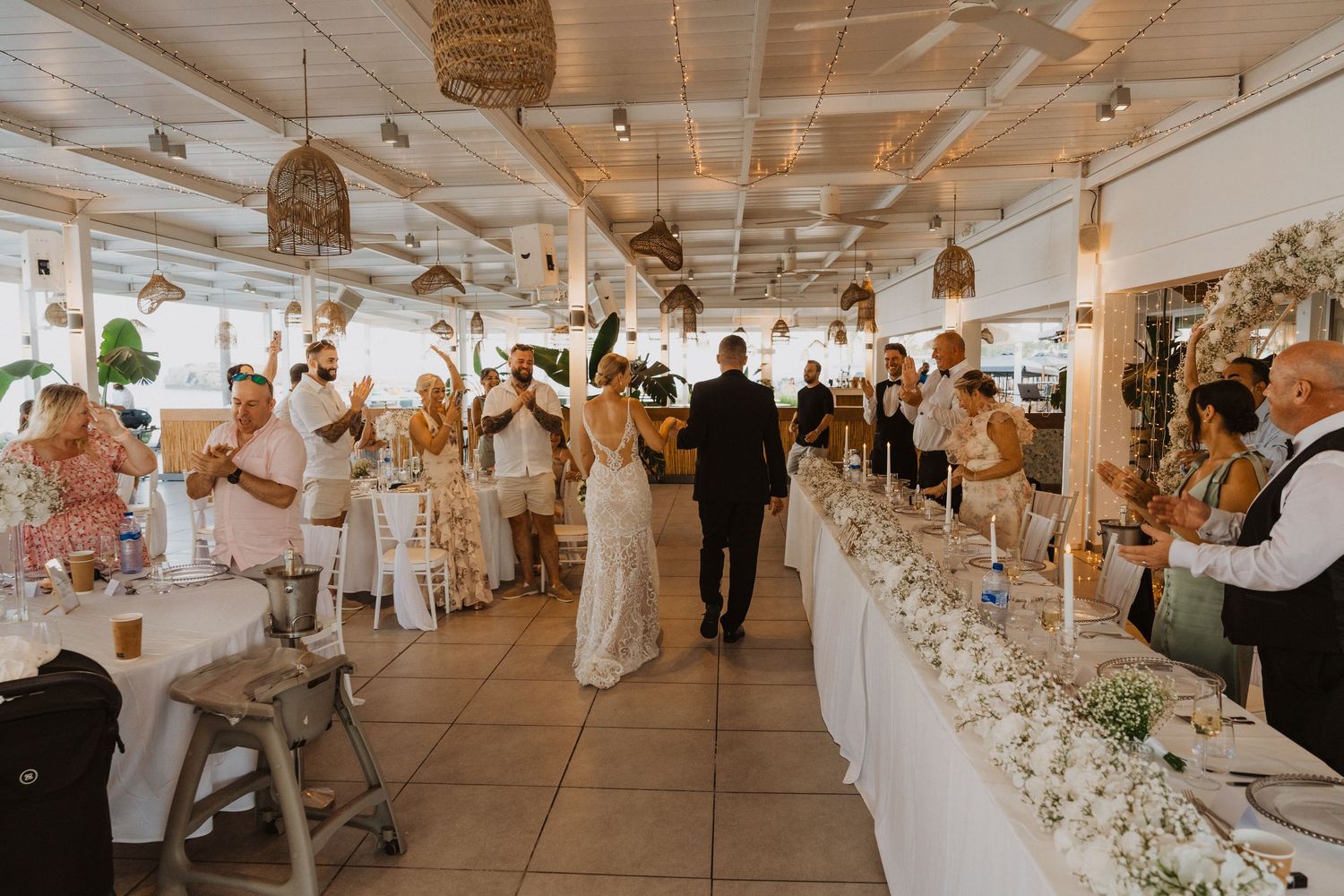 Elegant wedding reception venue with white decor, hanging lights, and tropical garden views.