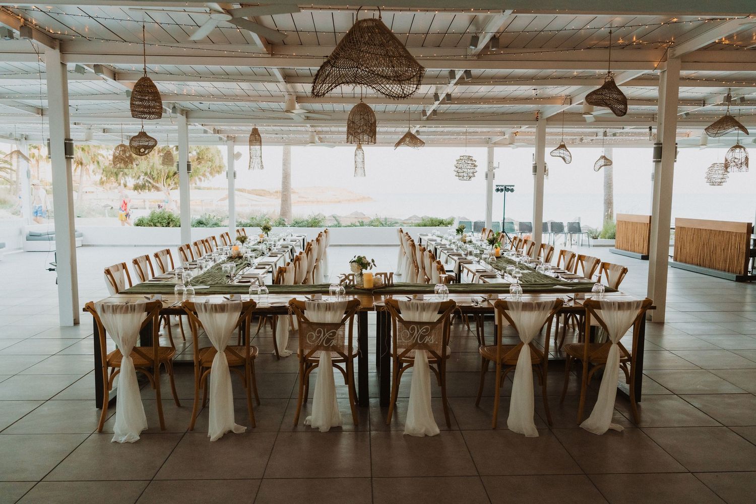 Wide panoramic view of an elegant wedding reception venue with rows of decorated tables and chairs.