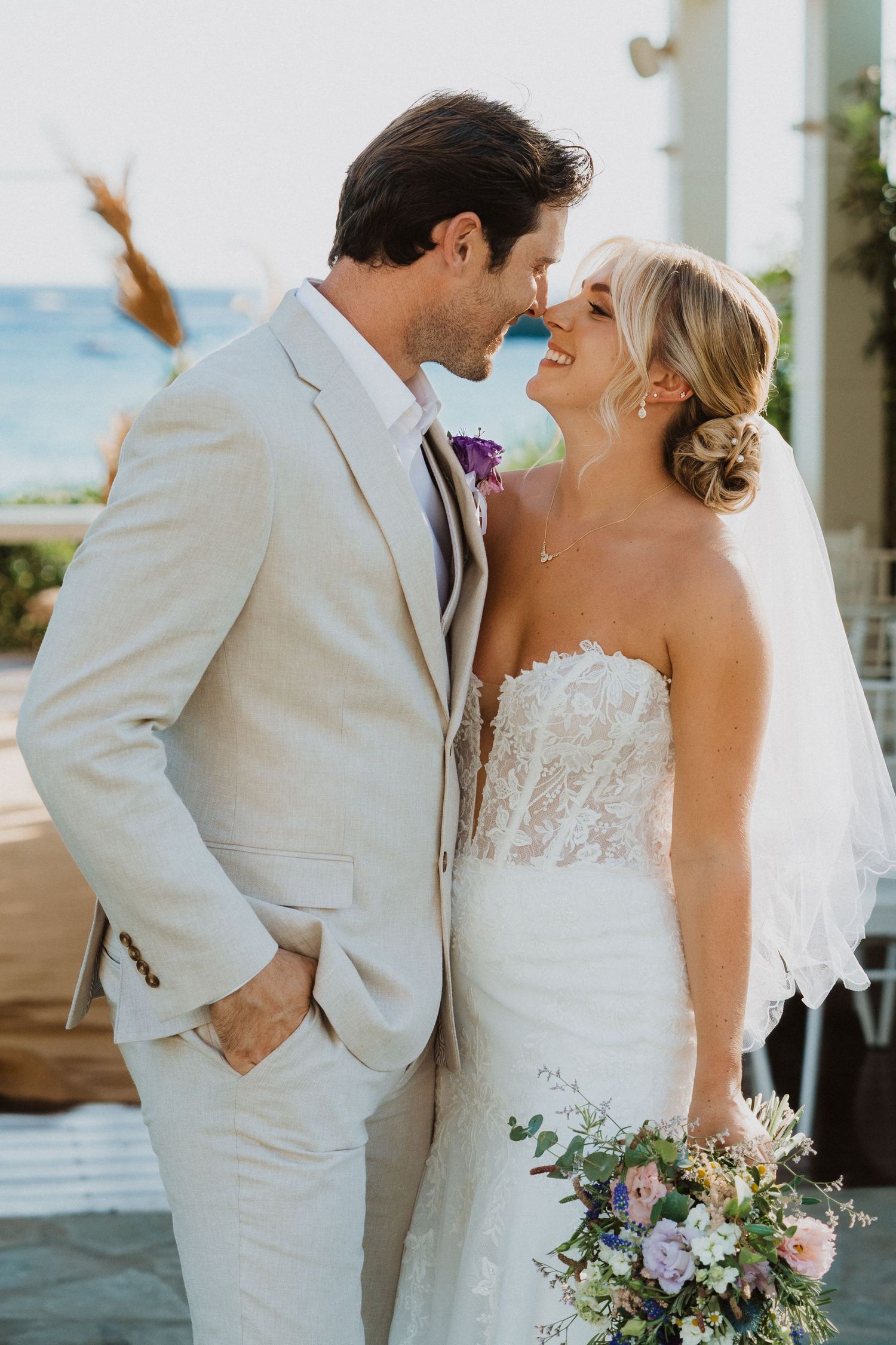 A joyful wedding portrait featuring a loving embrace against a seaside setting.