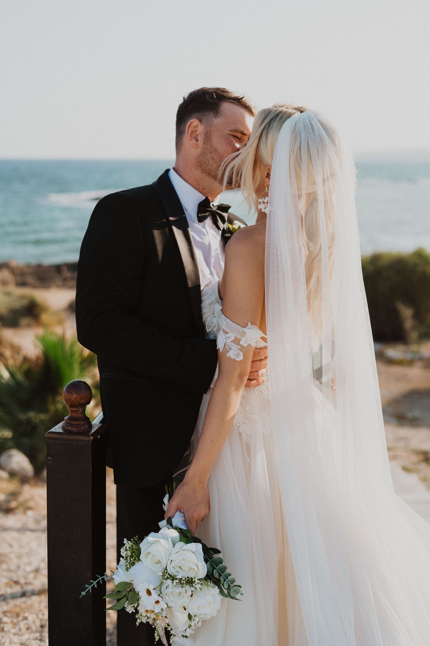 Intimate wedding moment captured against beautiful ocean backdrop at Mediterranean venue.