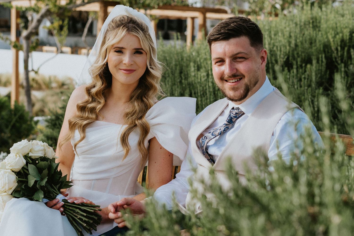 Wedding portrait in lush garden setting with white floral bouquet.