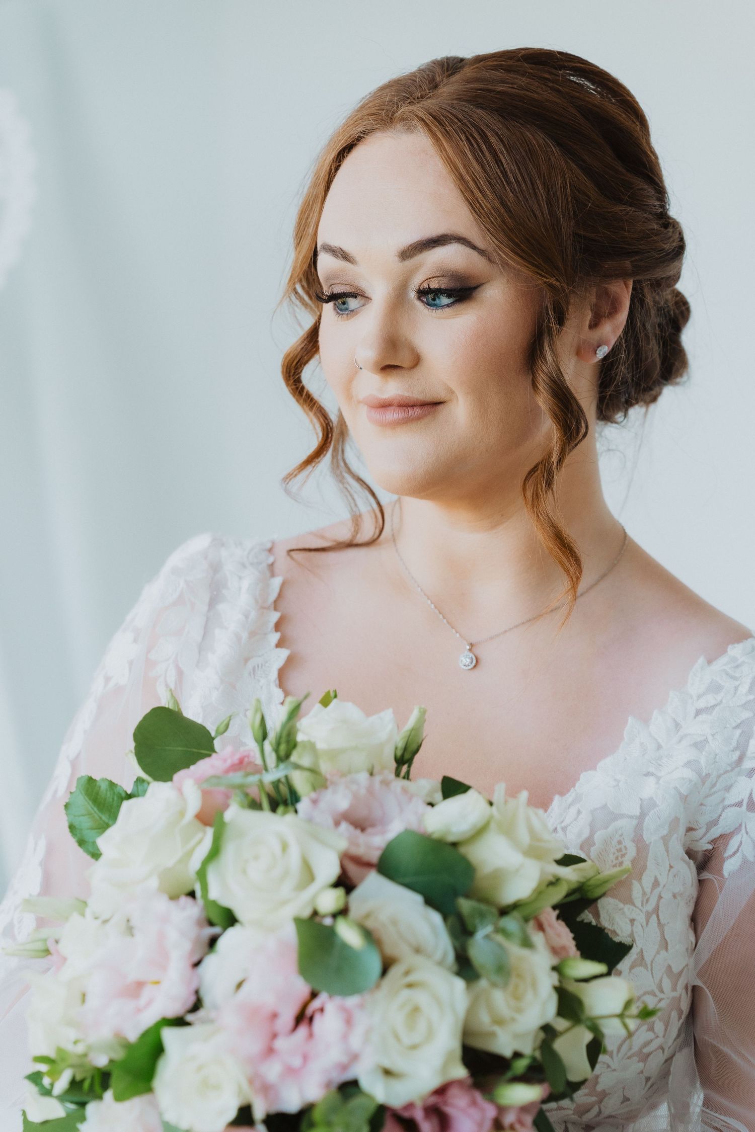 Close-up shot of bride smelling fresh bouquet of white and pink roses.