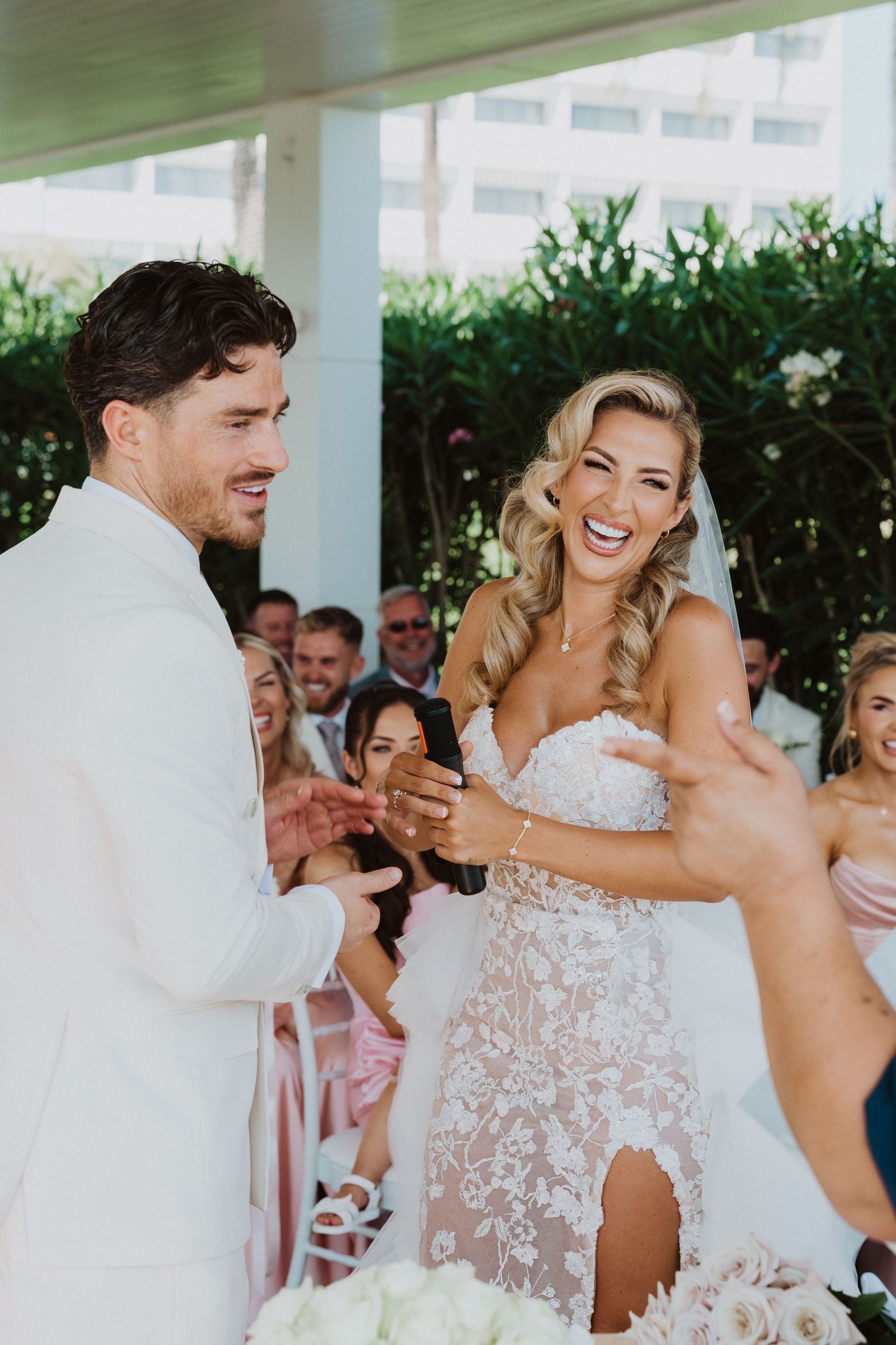 A joyful couple shares a candid moment while dancing at their wedding reception under a white covered patio.