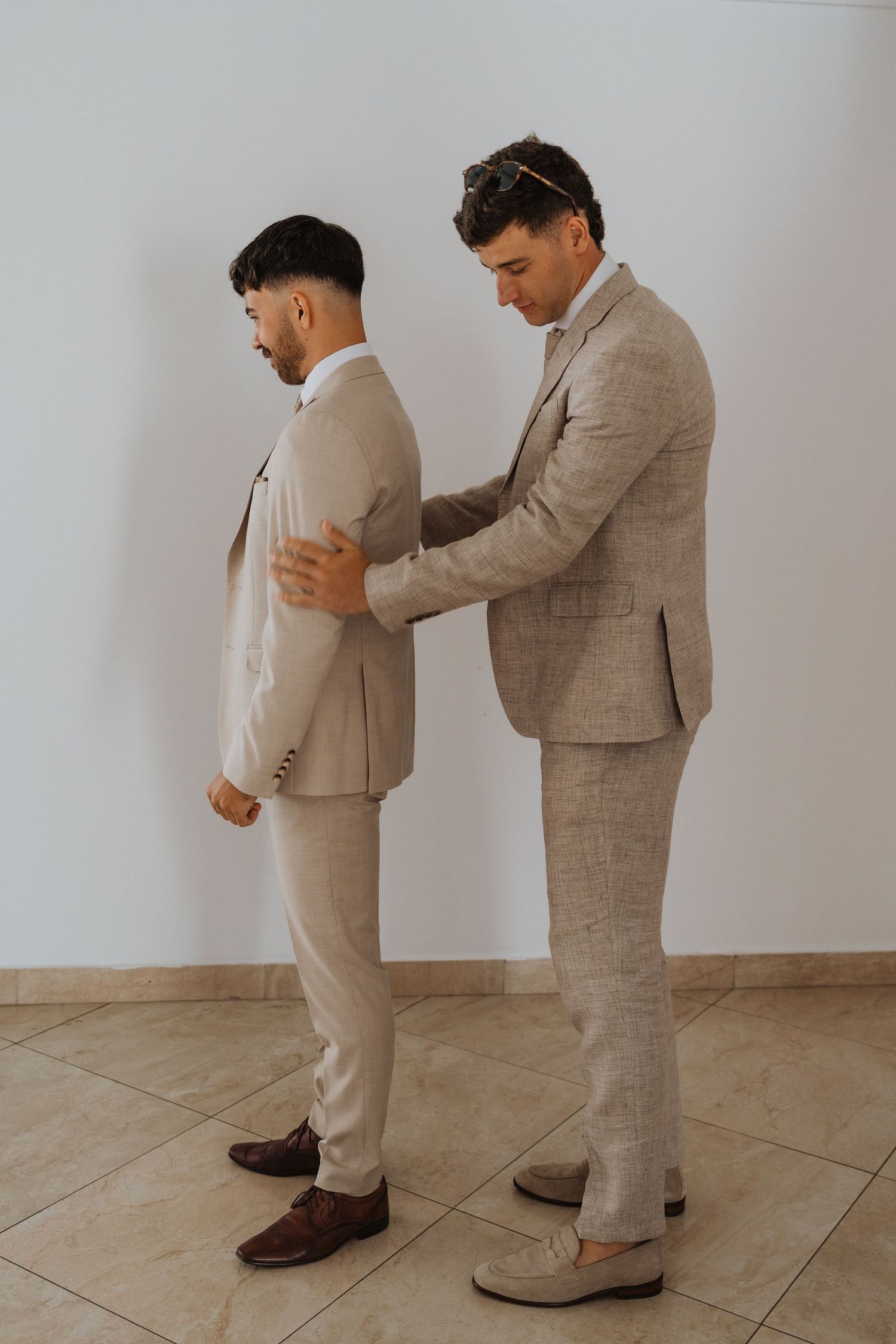 Wedding party members in tan suits adjusting their attire before the ceremony.