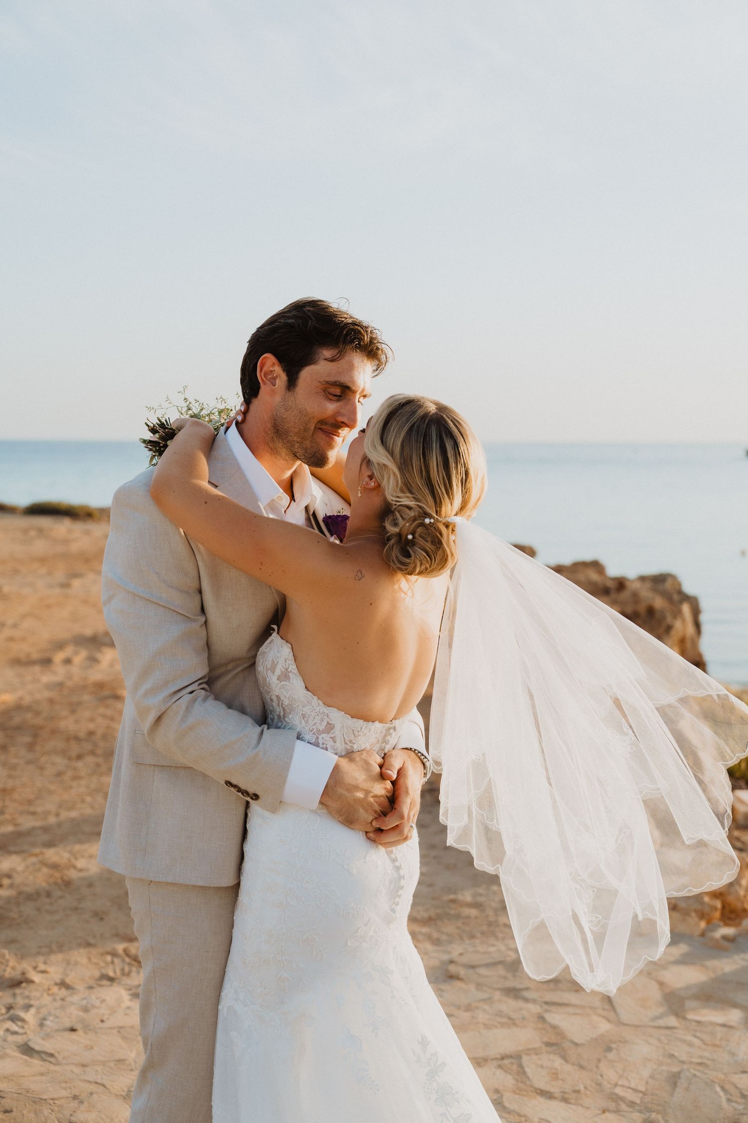 Dancing newlyweds share romantic moments on coastal rocks during golden hour.