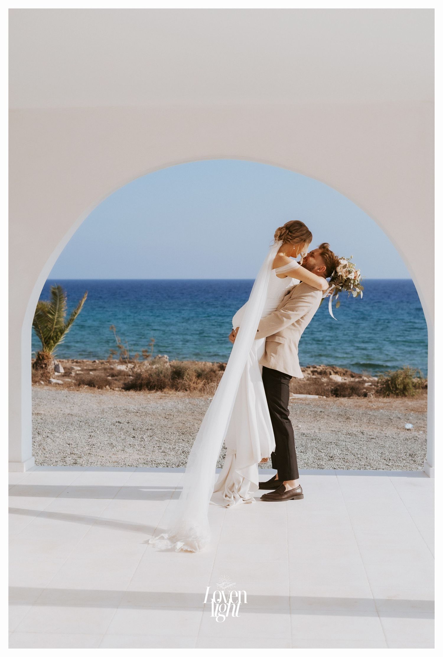 Joyful wedding moment captured under white Mediterranean architecture with ocean views.