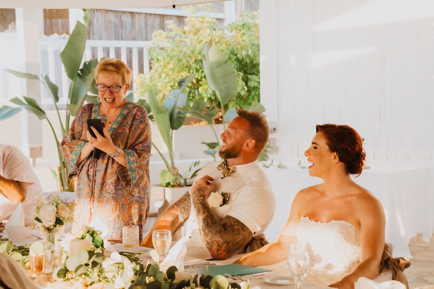 Candid moment during wedding reception speeches with guests seated at decorated dinner table.
