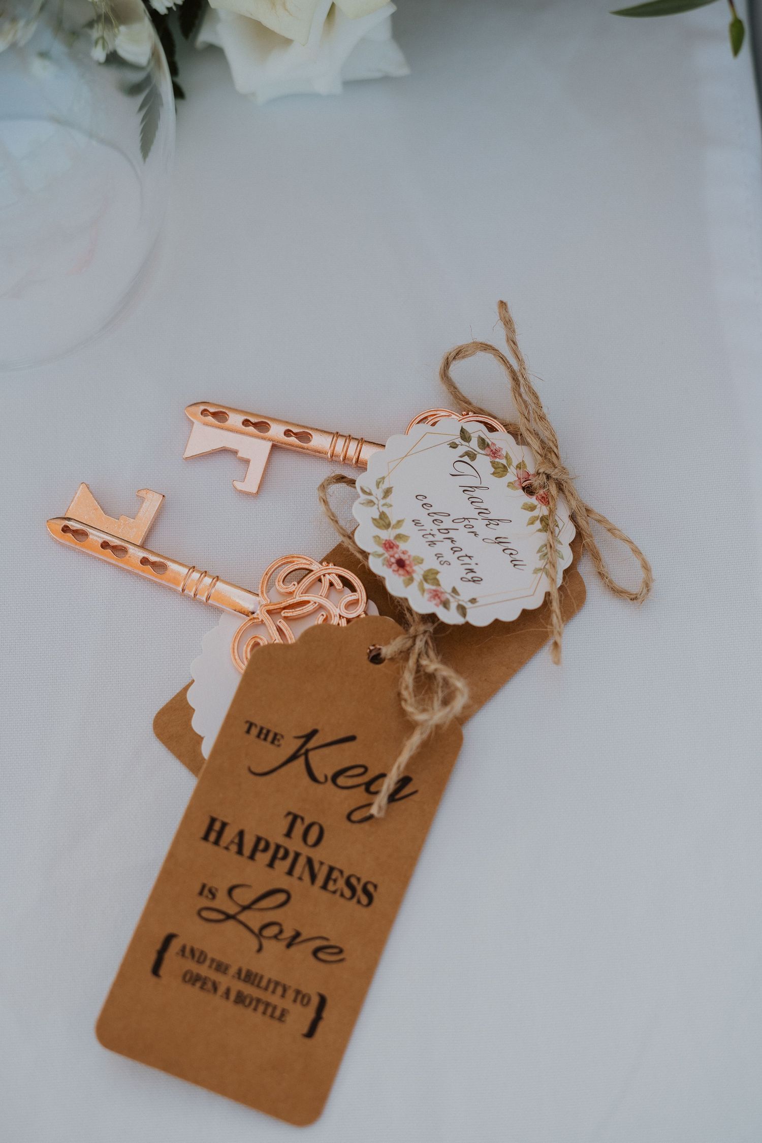 Vintage rose gold key with kraft paper tag reading 'The Key to Happiness' tied with rustic twine.
