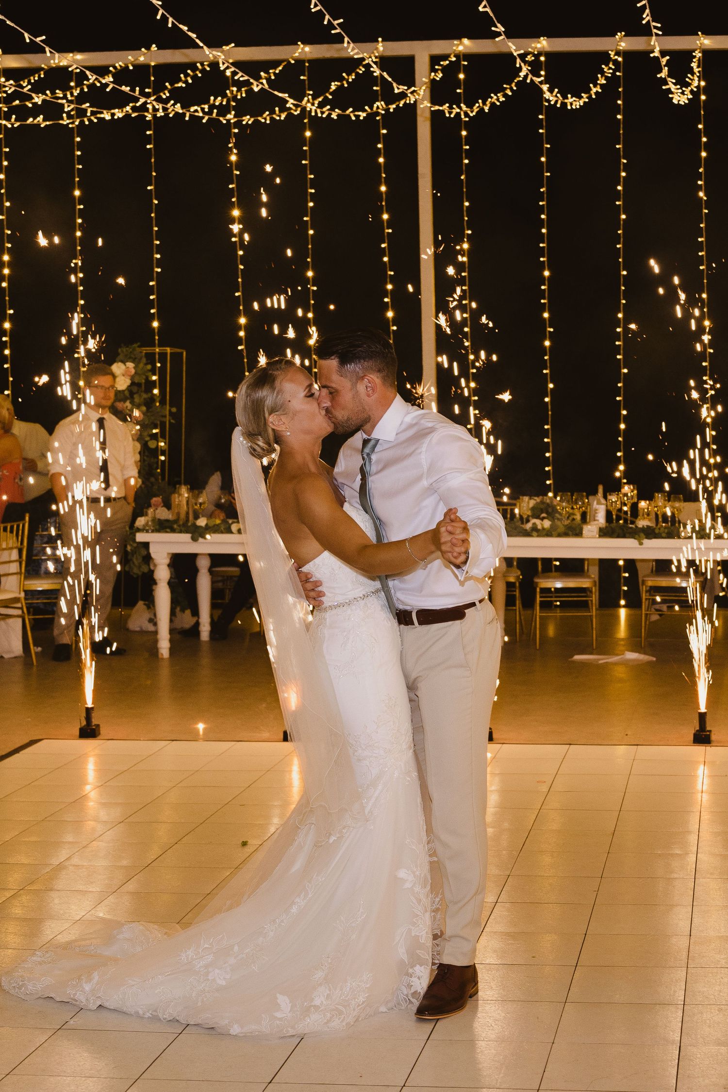 A romantic first dance moment with sparklers and string lights creating a magical atmosphere.