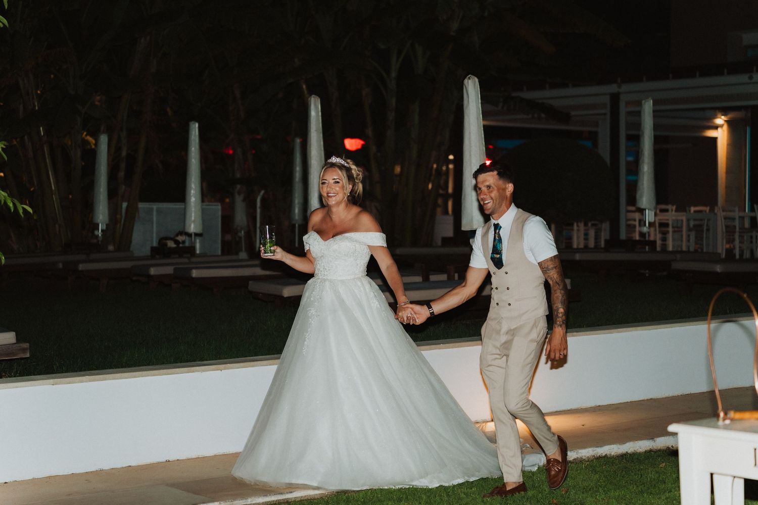 Playful evening outdoor wedding scene with couple tossing a red ball.