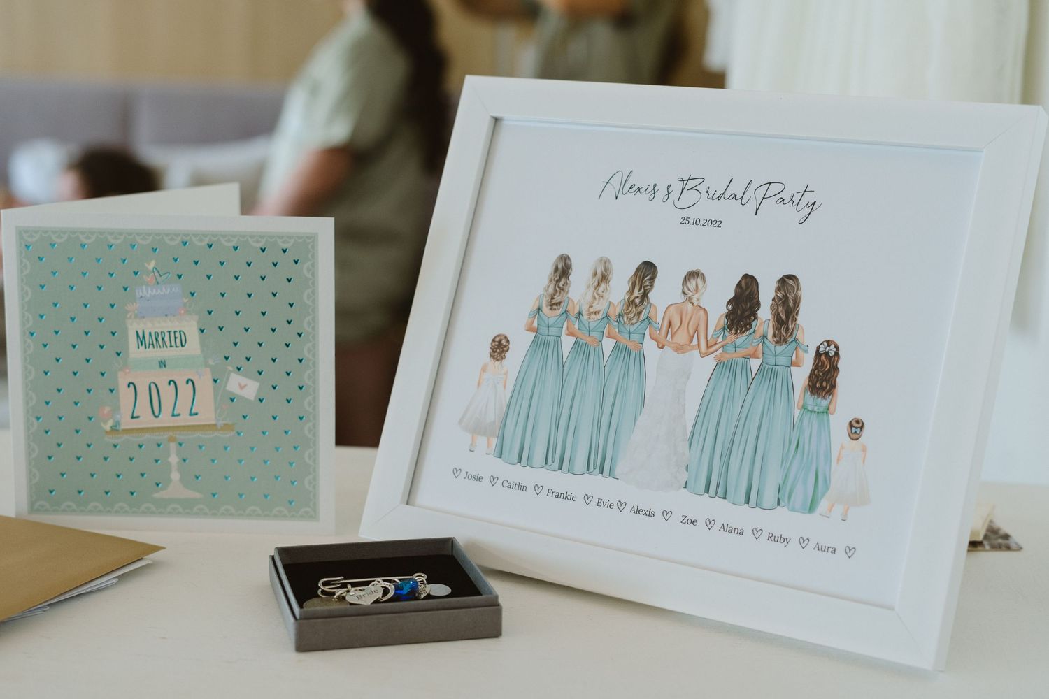 Wedding details featuring bridesmaid illustration card and mint green stationery on table.