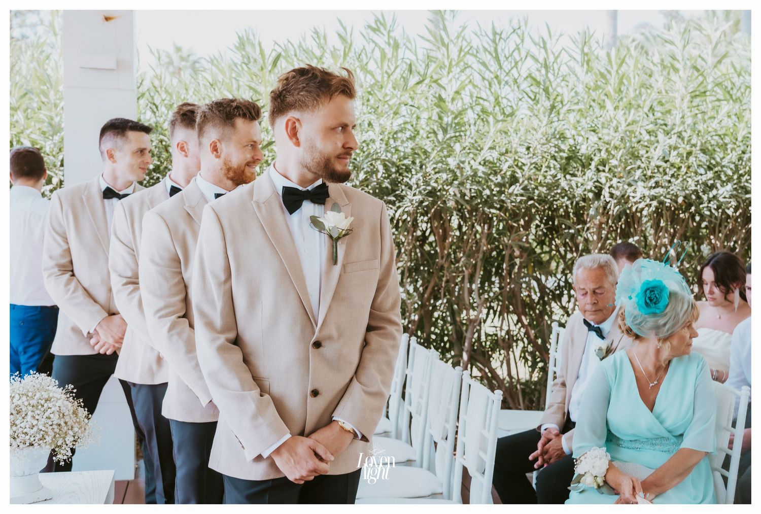 Groomsmen lineup in beige suits during outdoor wedding ceremony.