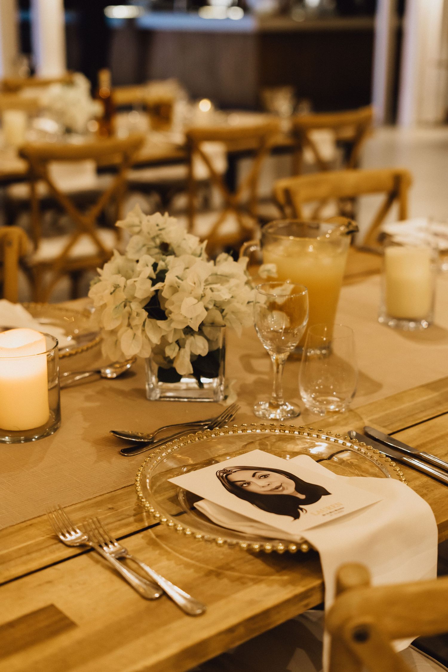 Elegant place setting with white hydrangea centerpiece and crystal charger plate on wooden table.