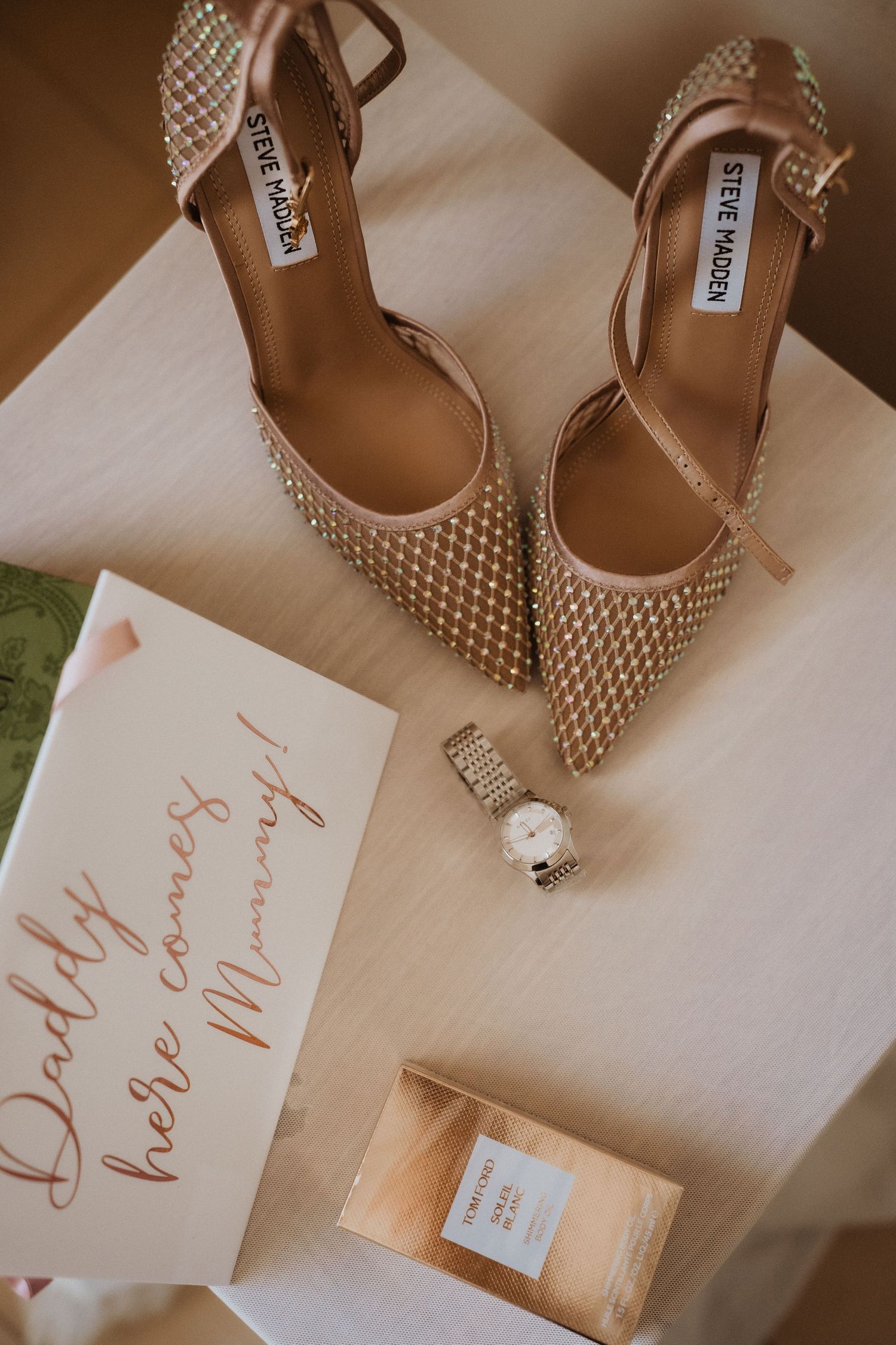 Elegant studded Steve Madden heels displayed with a handwritten note, perfume bottle and wristwatch on beige surface.