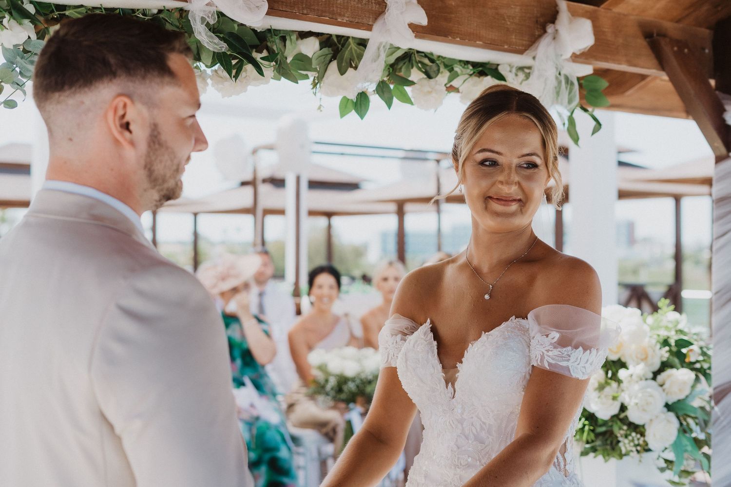 A couple shares their first dance at an outdoor wedding reception decorated with hanging greenery and white florals.