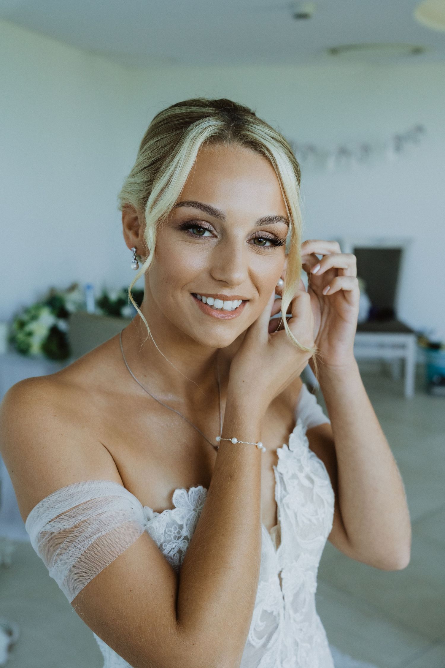 Close-up shots showing details of a bride putting on earrings in an elegant white wedding dress.