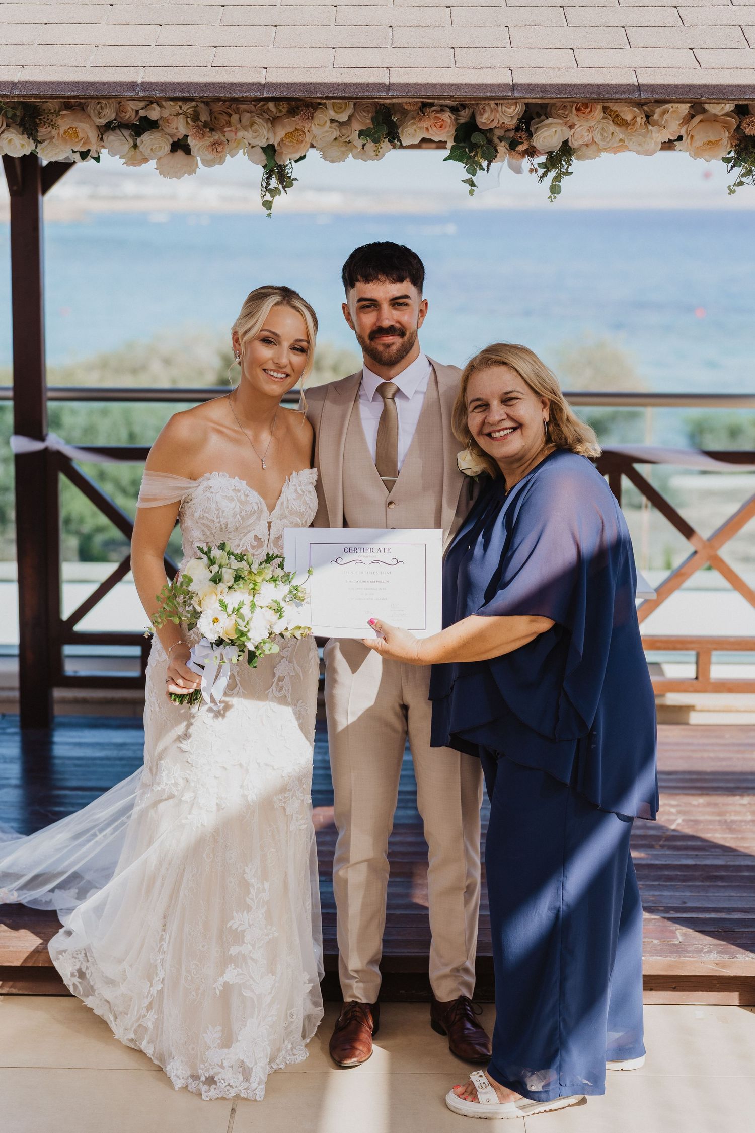 Wedding celebration on a waterfront deck with floral arrangements and scenic ocean backdrop.