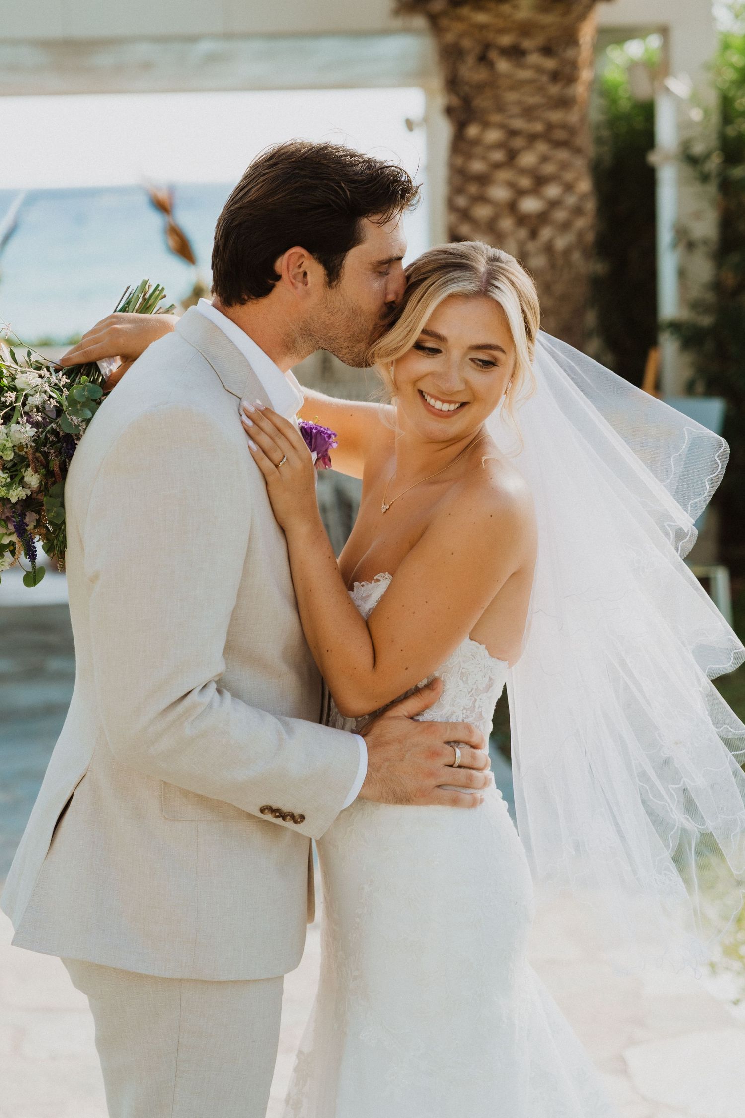 An intimate wedding moment captured in a sun-drenched tropical garden setting.