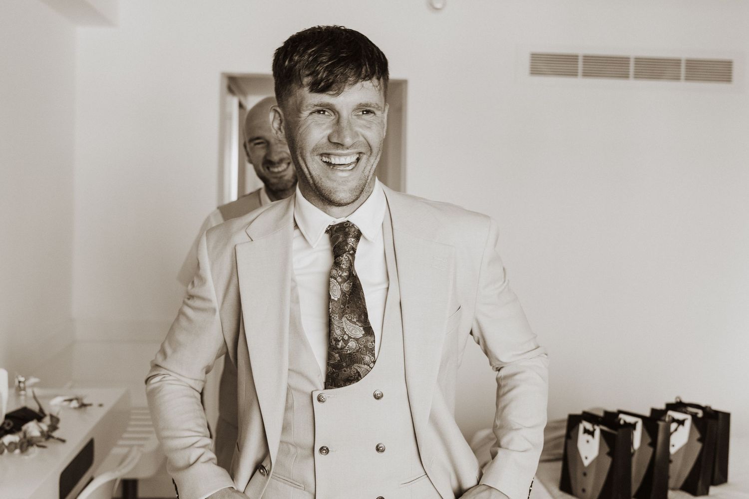 A vintage black and white photo shows someone wearing a light-colored three piece suit with a patterned tie.