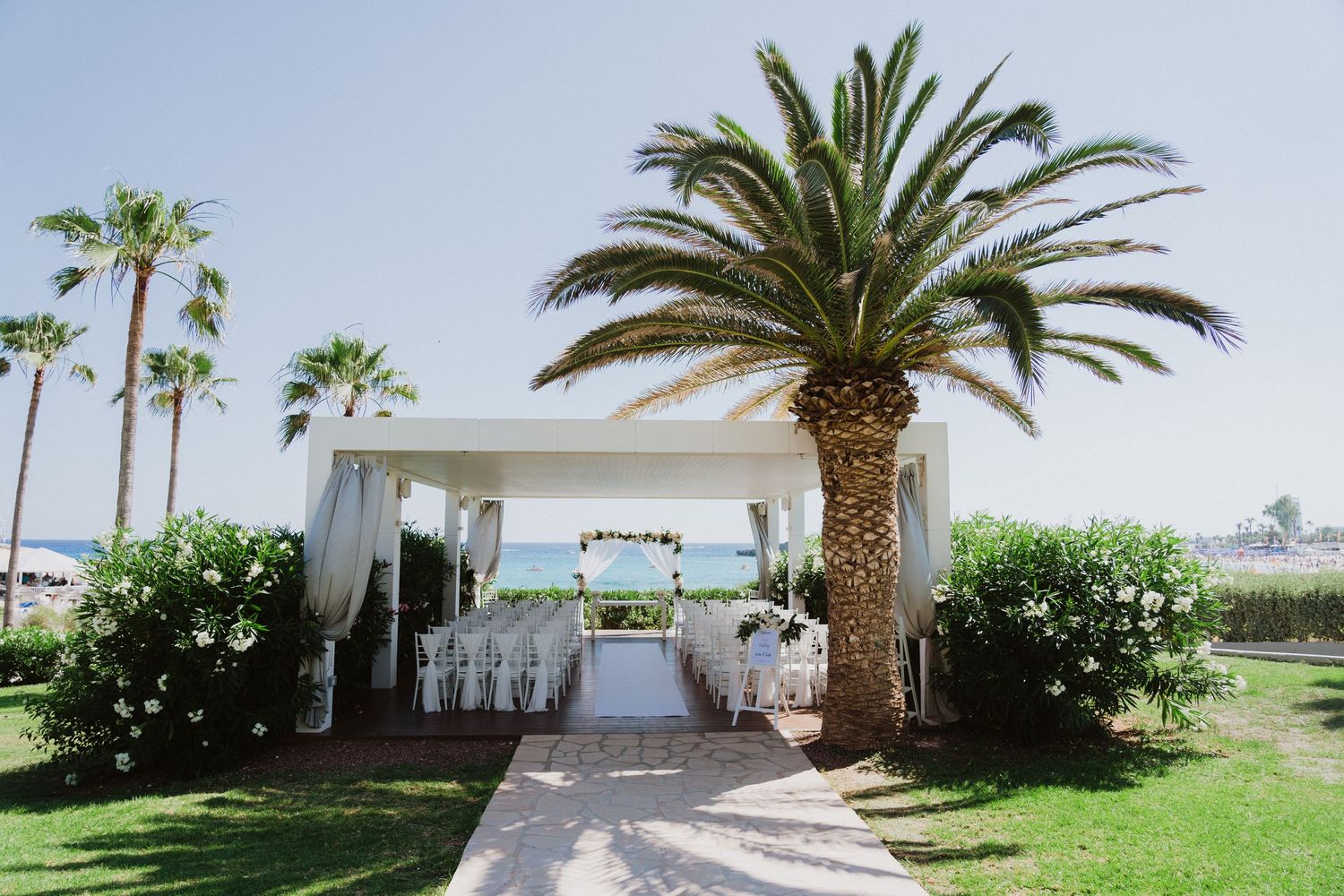 Tropical beach wedding venue exterior with palm trees and white architecture.
