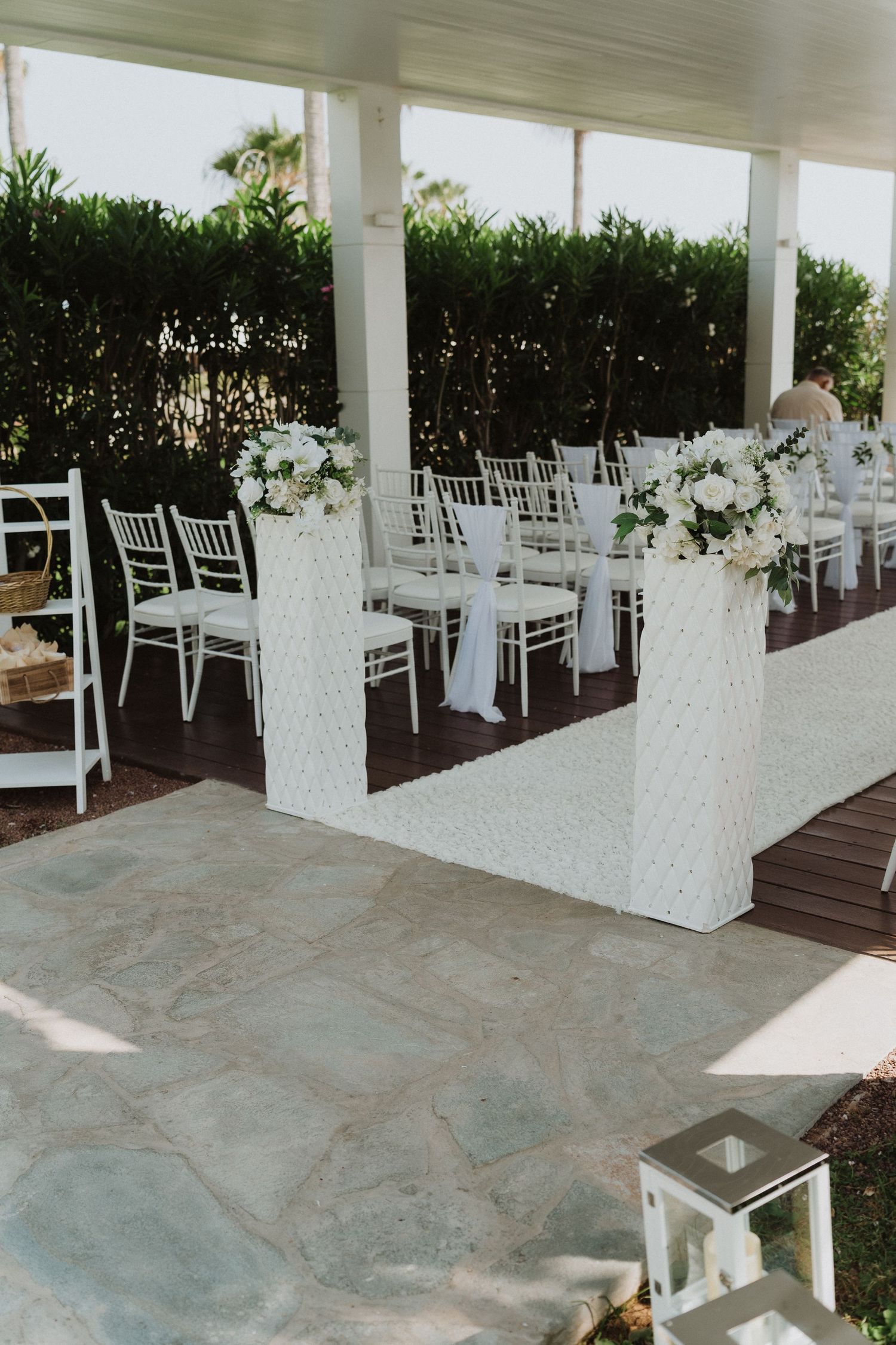 Elegant outdoor wedding ceremony setup with white chiavari chairs and floral aisle decorations.