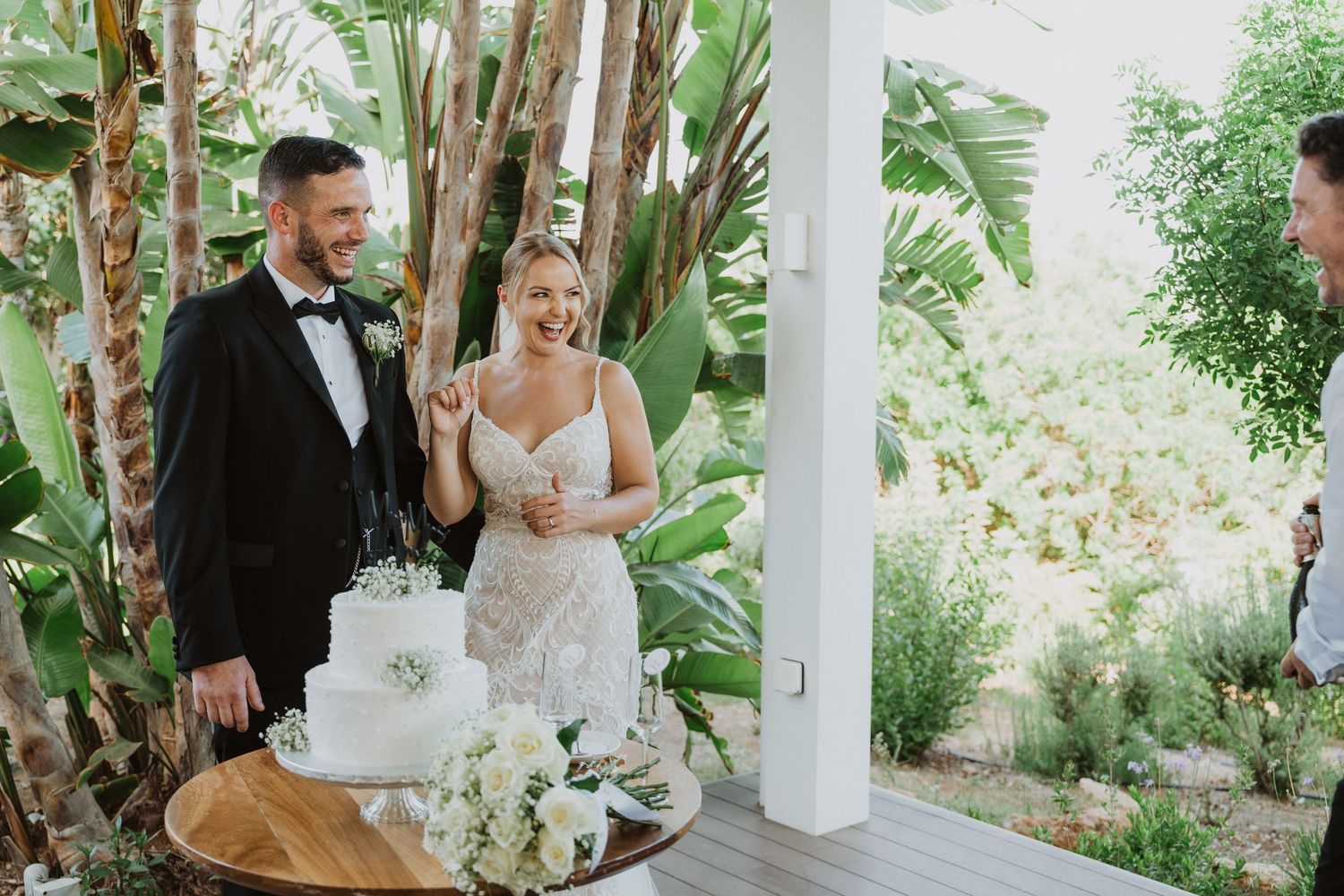 Outdoor wedding ceremony setup with tropical plants and white decor at an elegant venue.