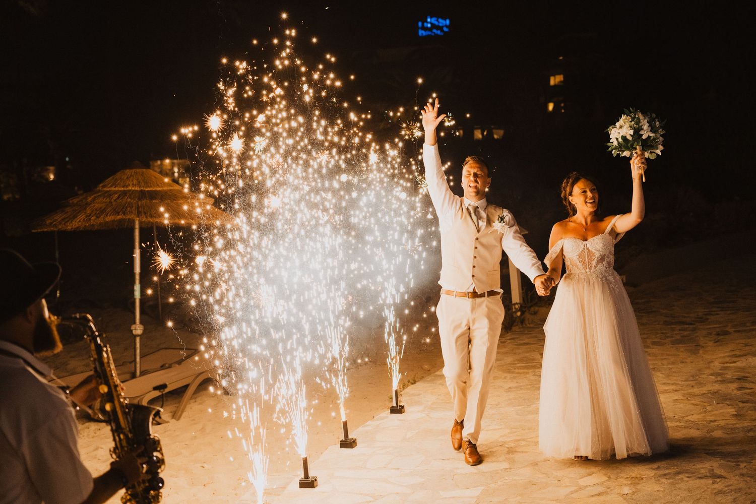 Joyous celebration on a beach at night with sparklers and pyrotechnics creating a magical wedding moment.