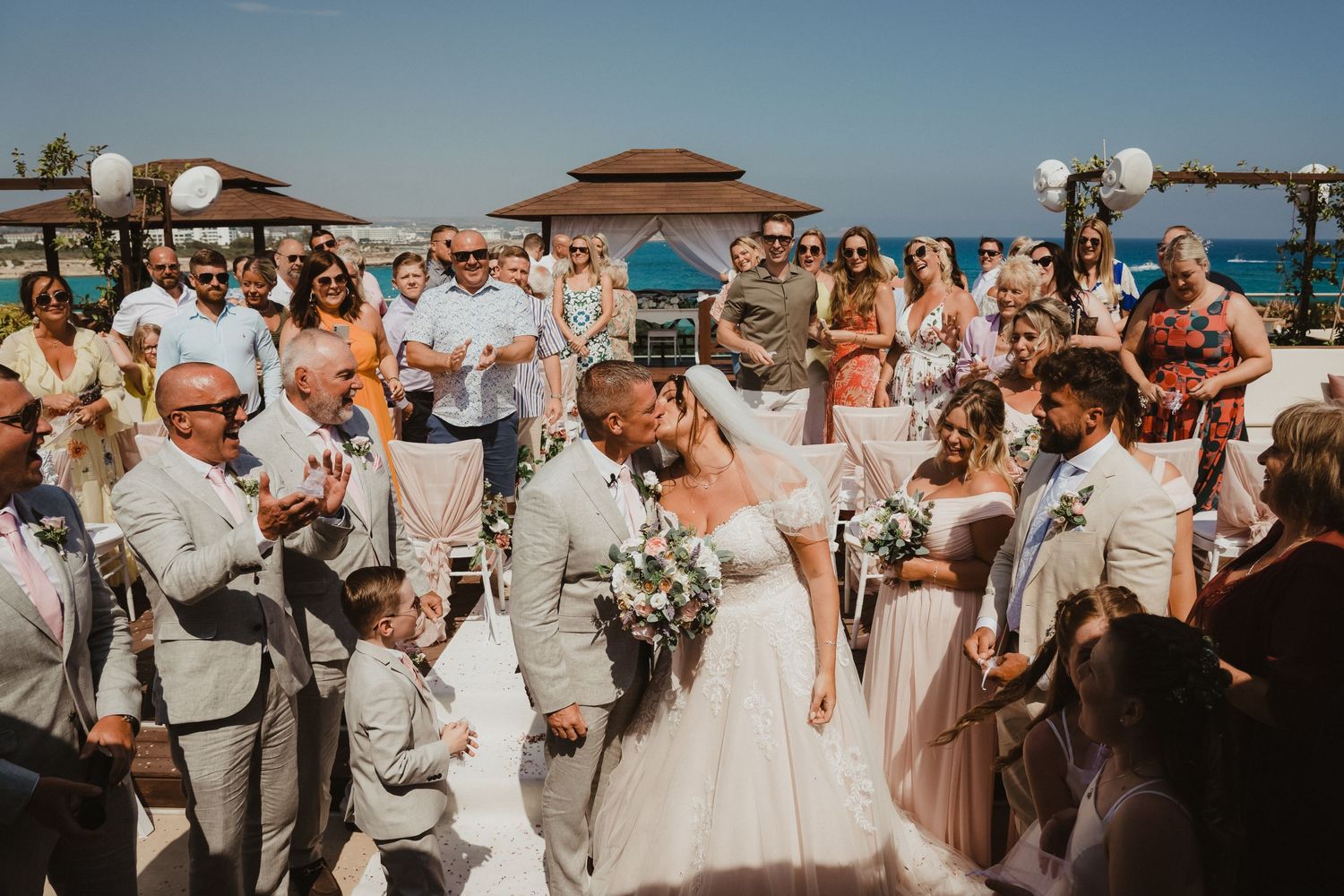 A joyous beachside wedding ceremony celebration under bright blue skies.