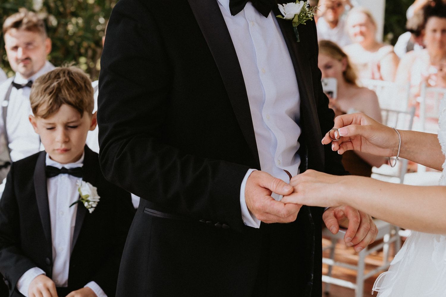 Close-up of wedding ring exchange with young attendant watching.