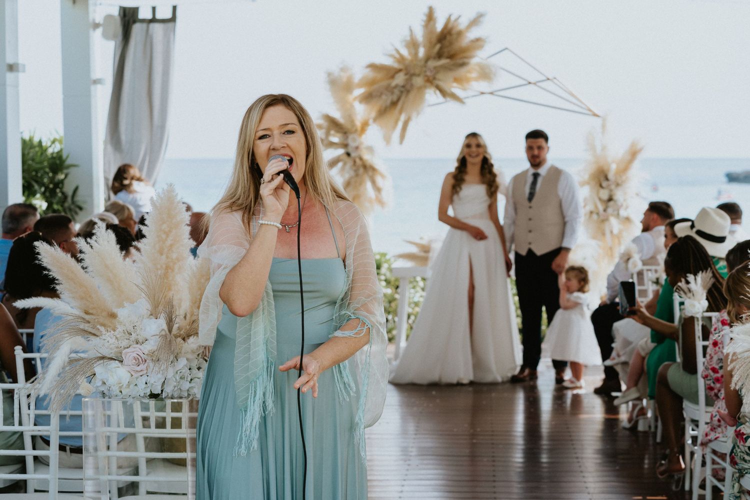 Singer performs at outdoor wedding reception with pampas grass decor.
