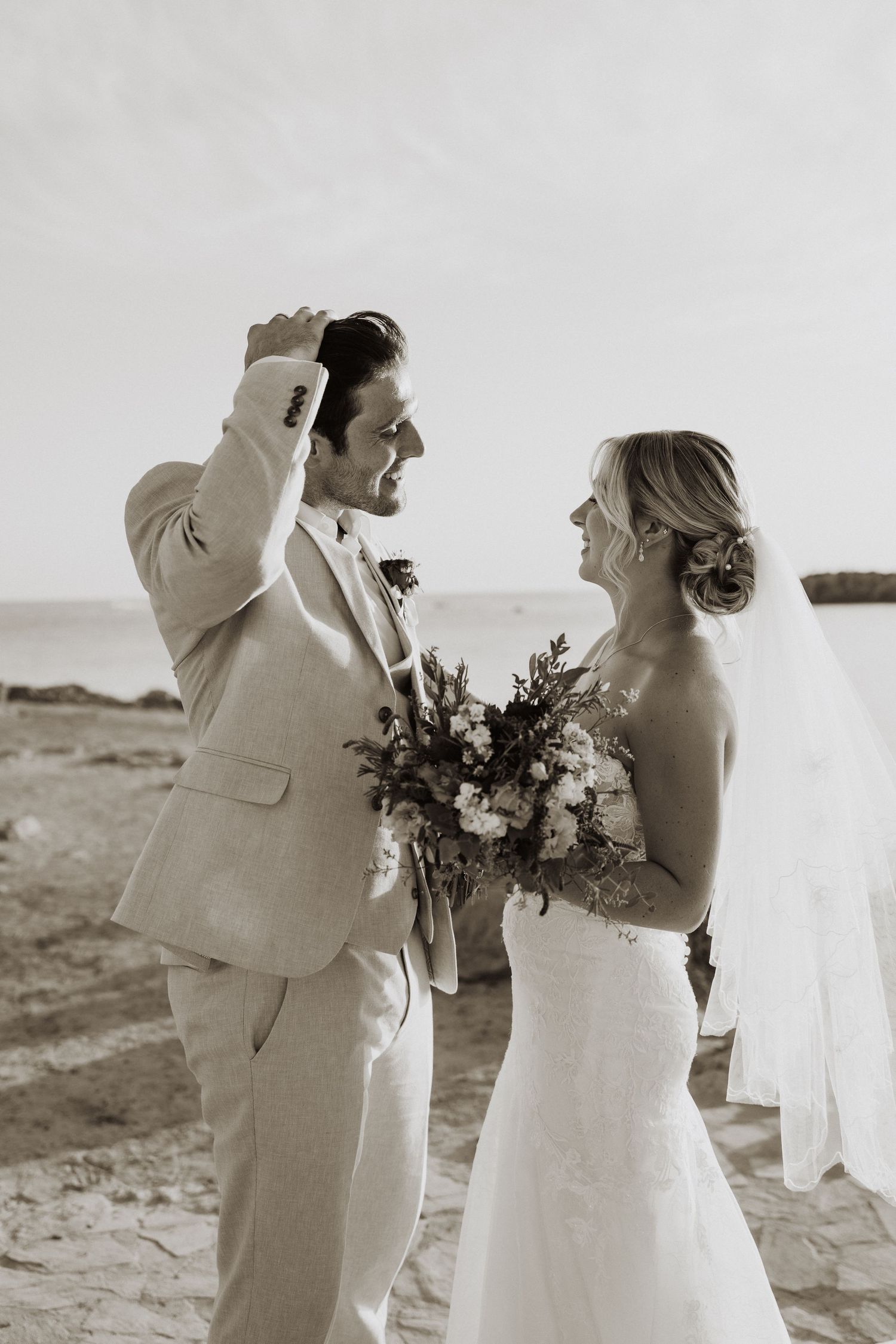 Black and white wedding portrait on a beach with dramatic poses.