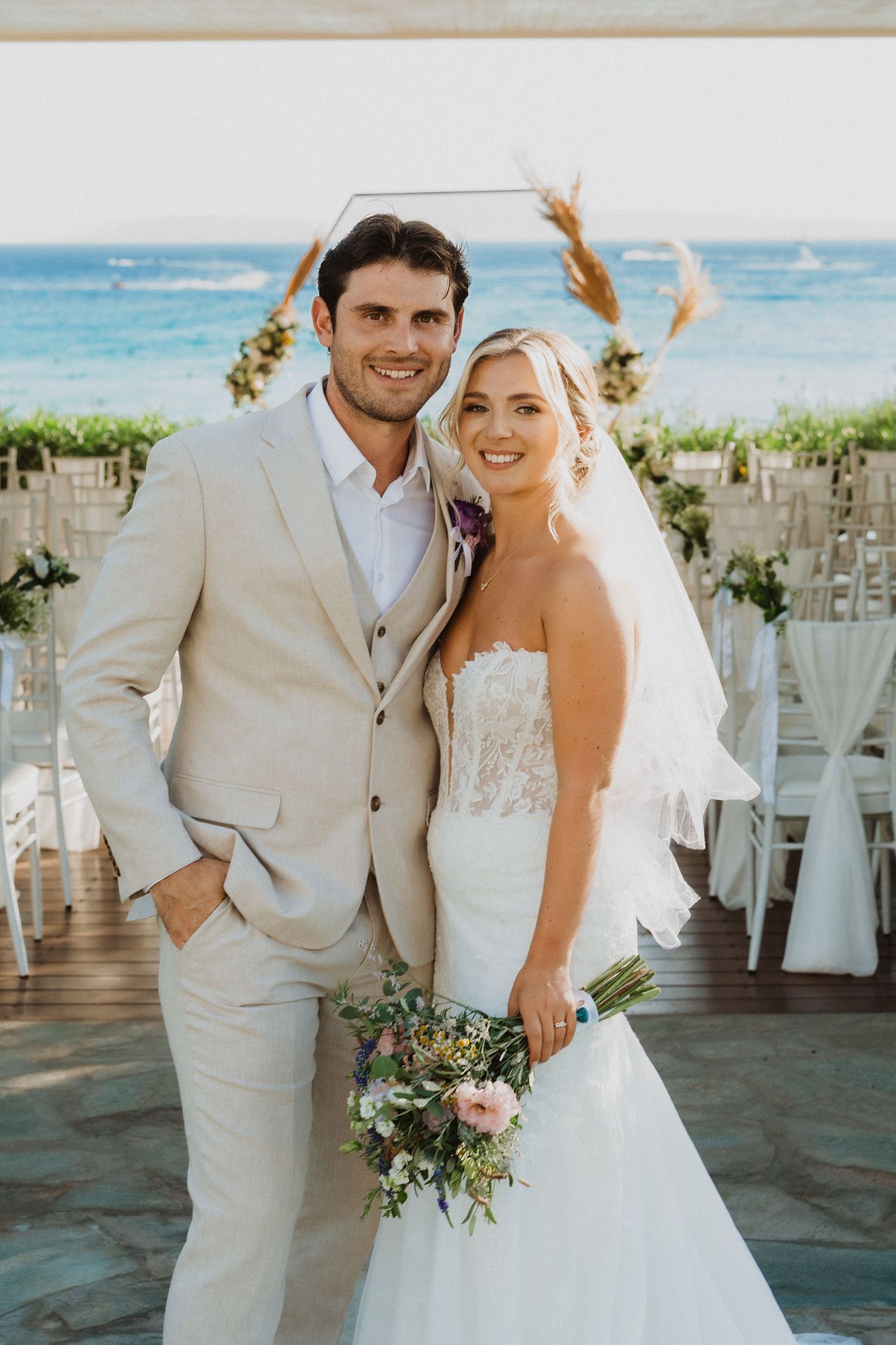 Beachfront wedding ceremony setup with white chairs and ocean backdrop.
