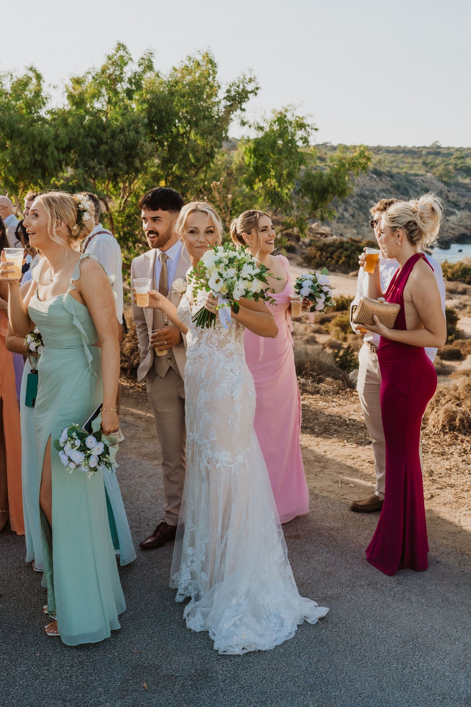 Wedding party gathered outside on a sunny day wearing mint and burgundy dresses.