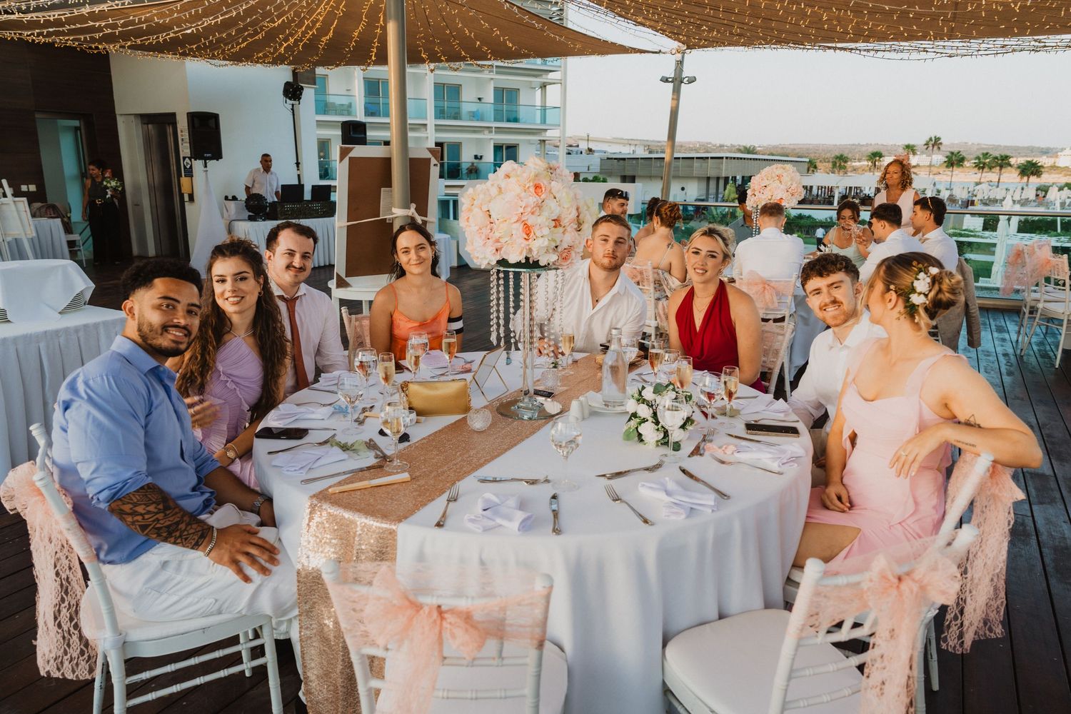 Wedding reception venue with round tables and chairs decorated in soft pink and white.