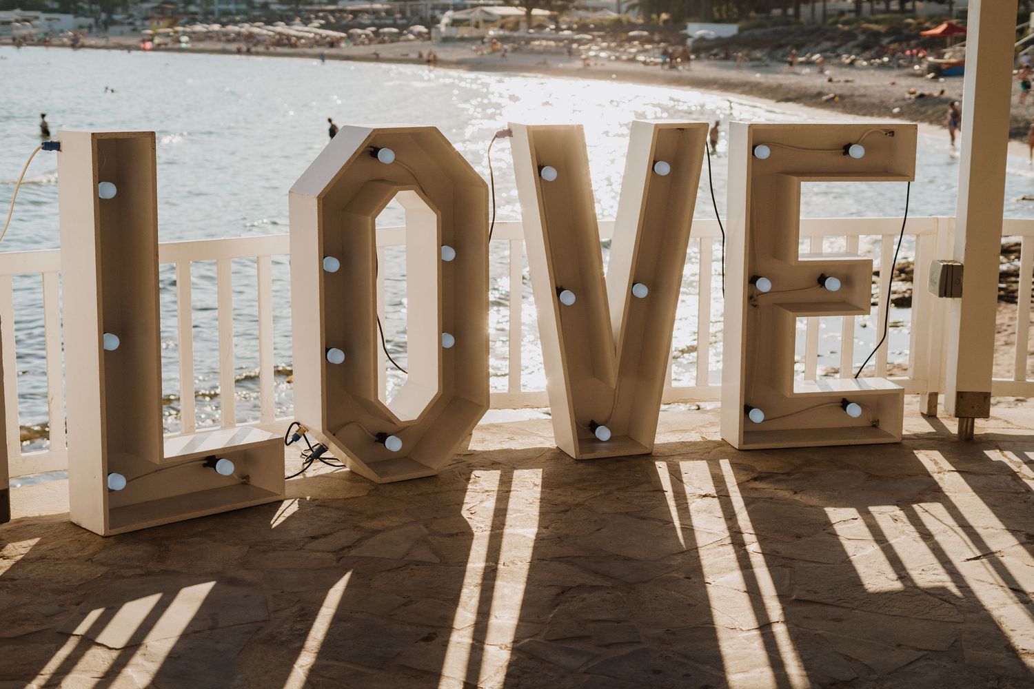 Sunlit wedding venue with white decor and ocean views through large windows.