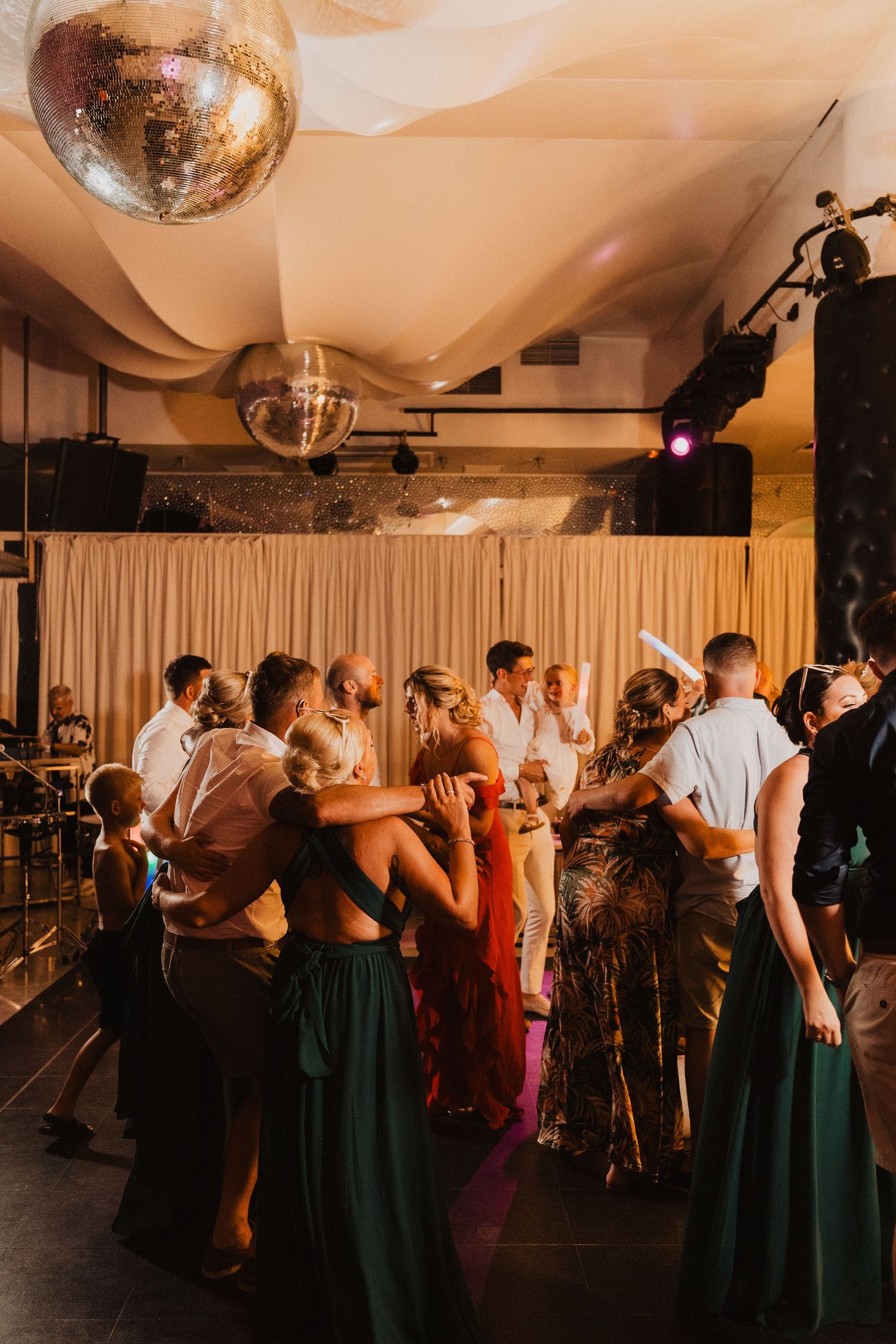 Wedding reception dance floor with disco ball and crowd of guests dancing.